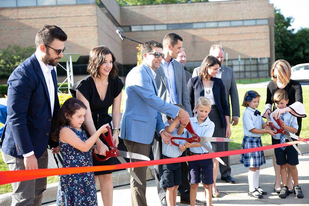 Large group of people cutting ribbon with large scissors