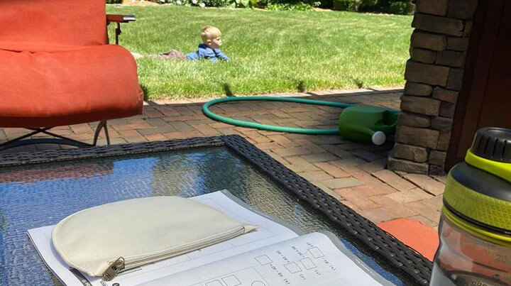 Math book on table, student laying in the grass